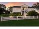 Charming two-story waterfront home featuring a white picket fence, lush landscaping, and elevated construction at 1610 Bayshore Dr, Terra Ceia, FL 34250