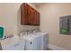 Laundry room with a sink, overhead cabinets, and a modern washer and dryer set at 1610 Bayshore Dr, Terra Ceia, FL 34250