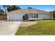 Well-maintained home with a two-car garage, a neatly landscaped yard, and a paved driveway leading to the entrance at 19897 Midway Blvd, Port Charlotte, FL 33948