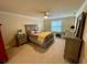 Comfortable bedroom with neutral decor, carpeted floors, ceiling fan, and a large window at 20940 Valore Ct, Venice, FL 34293