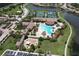 Aerial view of a community pool area with a large pool, clubhouse, tennis courts, and playground, surrounded by landscaping at 20940 Valore Ct, Venice, FL 34293