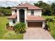Two-story home with a red tile roof, paver driveway, and manicured lawn in a lush, green landscape at 20940 Valore Ct, Venice, FL 34293