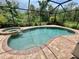 Sparkling screened-in pool with a spa, surrounded by a brick patio and lush greenery at 20940 Valore Ct, Venice, FL 34293