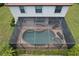 Aerial view of a screened-in pool and spa area with brick pavers, lounge chairs, and manicured landscaping at 20940 Valore Ct, Venice, FL 34293