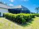 Exterior view of enclosed patio with a metal screen roof, surrounded by a manicured green yard with healthy shrubs at 2200 E Village Ct, Venice, FL 34293