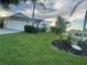 Well-maintained front yard with green grass, palm trees, and landscaping leading to an attached two-car garage at 2200 E Village Ct, Venice, FL 34293