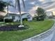 Charming single-story home with lush lawn and tropical landscaping, including palm trees and mulch beds at 2200 E Village Ct, Venice, FL 34293