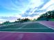 Well-maintained community tennis court with fresh green and purple surfacing, set against a clear sky at 2200 E Village Ct, Venice, FL 34293