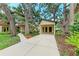 Charming home exterior featuring a concrete driveway, attached carport, and mature trees with beautiful landscaping at 2237 Circlewood Dr # 18, Sarasota, FL 34231