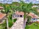Charming blue home with a red tile roof, manicured lawn, and mature palm trees lining the driveway at 227 Monet Dr, Nokomis, FL 34275