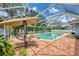 Inviting screened pool area with brick pavers, lounge chairs, and tropical landscaping at 227 Monet Dr, Nokomis, FL 34275