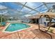 Relaxing screened pool area with brick pavers, lounge chairs, and tranquil water at 227 Monet Dr, Nokomis, FL 34275