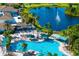 An aerial view of the community pool, surrounded by palm trees and lounge chairs, with a lake and golf course in the distance at 2411 New Haven Cir # 70, Sun City Center, FL 33573