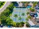 Aerial view of community tennis/pickle ball courts surrounded by palm trees, a clubhouse, and a parking lot at 2411 New Haven Cir # 70, Sun City Center, FL 33573