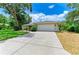Wide concrete driveway leading to a 2-car garage and a charming home exterior with manicured landscaping at 2512 Jamaica St, Sarasota, FL 34231