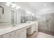 The bright bathroom offers double sinks, a large mirror, and a tile walk-in shower with grab bars at 25143 Spartina Dr, Venice, FL 34293