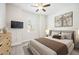 This bedroom has neutral walls with a queen bed, TV, ceiling fan, and 2 pictures on the wall at 25143 Spartina Dr, Venice, FL 34293