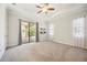 Large bedroom featuring neutral walls and carpet, ceiling fan, and sliding door to a private patio at 25143 Spartina Dr, Venice, FL 34293