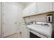 This laundry room has white cabinets, white walls and washer and dryer at 25143 Spartina Dr, Venice, FL 34293