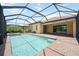 Pool and jacuzzi inside of a screened enclosure with brick pavers surrounding, plus a view of the exterior of the house at 25143 Spartina Dr, Venice, FL 34293