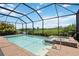 View of the pool and jacuzzi inside of the screened enclosure, with landscaping around the enclosure, and a view of the golf course at 25143 Spartina Dr, Venice, FL 34293