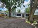Charming home with mature trees, gravel driveway, a screened-in porch, and grey paint at 27 Tucker Ave, Sarasota, FL 34232