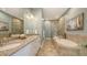 This bright bathroom contains a soaking tub, glass shower, double sinks, and stone tile flooring at 3430 77Th W St # 301, Bradenton, FL 34209