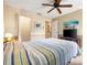 This bedroom includes a ceiling fan, wood floors, a large bed, an en-suite bathroom, and a large TV at 3530 Wilkinson Woods Dr # 14, Sarasota, FL 34231