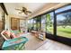 Enclosed lanai featuring a ceiling fan, outdoor seating, tiled floors, and a serene view of the landscaped yard at 3530 Wilkinson Woods Dr # 14, Sarasota, FL 34231