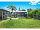A lush backyard featuring a screened-in pool area, a palm tree, and well-maintained greenery at 3551 65Th Avenue E Cir, Sarasota, FL 34243