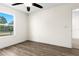 Bright bedroom with wood-look floors, ceiling fan, and view of the neighborhood street at 3551 65Th Avenue E Cir, Sarasota, FL 34243