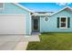 Aqua home with a two-car garage, white trim, and a well kept lawn and landscaping at 3551 65Th Avenue E Cir, Sarasota, FL 34243