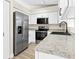 Galley kitchen featuring modern appliances, white cabinets, granite countertops, and wood-look flooring at 3551 65Th Avenue E Cir, Sarasota, FL 34243