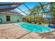 The screened-in pool features a paved patio, and tropical plants for a private backyard oasis at 3551 65Th Avenue E Cir, Sarasota, FL 34243