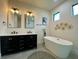 Modern bathroom showcasing double vanity, soaking tub, updated lighting, and art for a stylish retreat at 3616 Bellefonte Ave, North Port, FL 34286