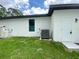 Rear exterior of a modern home with a well-maintained lawn, featuring a window, utility box, and door at 3616 Bellefonte Ave, North Port, FL 34286