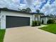 Contemporary home showcasing a spacious driveway leading to an attached two-car garage and well-manicured lawn at 3616 Bellefonte Ave, North Port, FL 34286