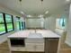 Kitchen island featuring white cabinets, stainless steel microwave and dishwasher, and a farmhouse sink at 3616 Bellefonte Ave, North Port, FL 34286