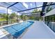 A screened-in pool area features a long pool, sleek decking, and views of the canal and landscaping beyond at 3636 Mineola, Sarasota, FL 34239