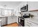 Modern kitchen featuring stainless steel appliances and white cabinetry, with easy access to the living area at 4728 Old Blush St, Bradenton, FL 34211