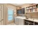 Well-organized laundry room with washer, dryer, cabinets, sink and shelving with cookbooks at 4761 Pine Harrier Dr, Sarasota, FL 34231