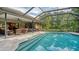 Back view of screened in-ground pool, patio, and landscaping at 4761 Pine Harrier Dr, Sarasota, FL 34231