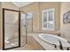 Bright bathroom featuring a frameless shower, soaking tub, and a window with shutters at 5104 Benito Ct, Bradenton, FL 34211