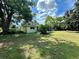Spacious backyard featuring mature trees, lush lawn and the rear of the charming home, perfect for outdoor activities at 5350 Barbarossa Ave, Sarasota, FL 34235