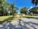 Charming yellow home with a well-maintained lawn, mature trees, and driveway on a sunny day at 5350 Barbarossa Ave, Sarasota, FL 34235