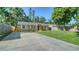 Charming single-story home featuring a well-maintained lawn, a long driveway and a bright red front door at 5438 Potter St, Sarasota, FL 34232
