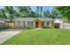 Inviting single-story home with a lush green lawn, a red door, and white shutters providing a welcoming feel at 5438 Potter St, Sarasota, FL 34232
