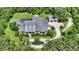 Aerial view of a luxury home surrounded by trees with a pool, circular drive, and separate garage at 6050 Saddle Oak Trl, Sarasota, FL 34241