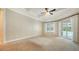 Bright bedroom with a tray ceiling, ceiling fan, and sliding glass doors that provide access to the pool area at 6050 Saddle Oak Trl, Sarasota, FL 34241
