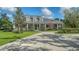 Beautiful front exterior of home with mature trees, a circular driveway, and pristine landscaping at 6050 Saddle Oak Trl, Sarasota, FL 34241